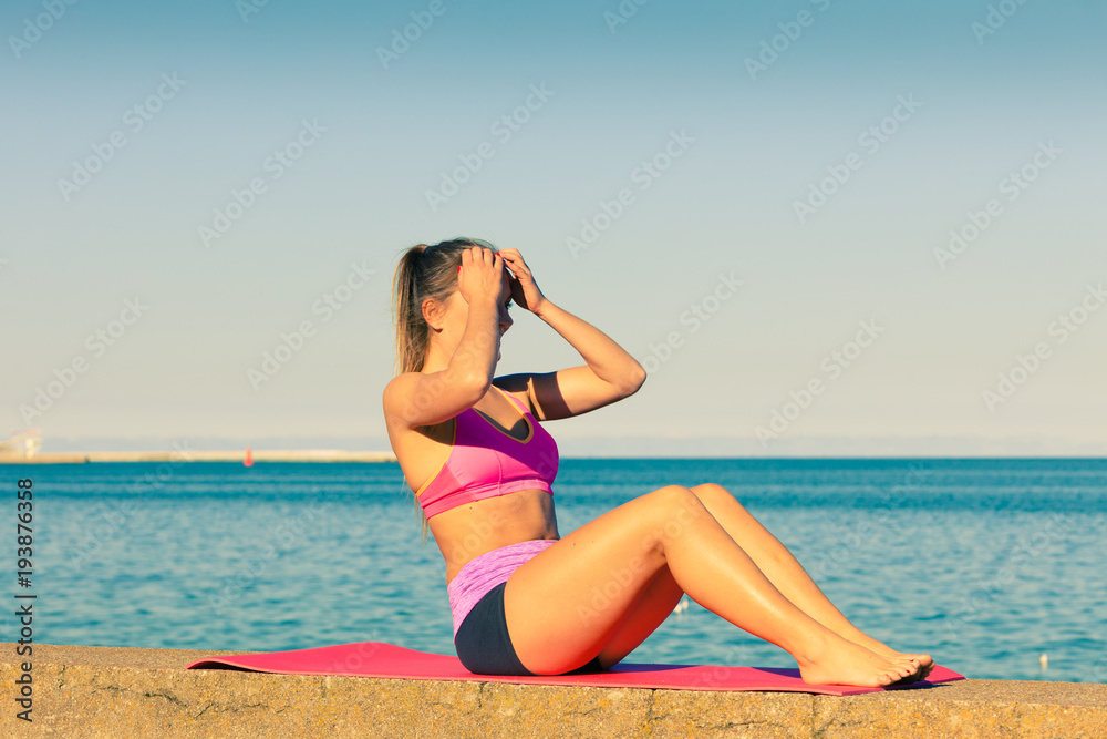 Woman doing sports exercises outdoors by seaside Woman doing sports exercises outdoors by seaside