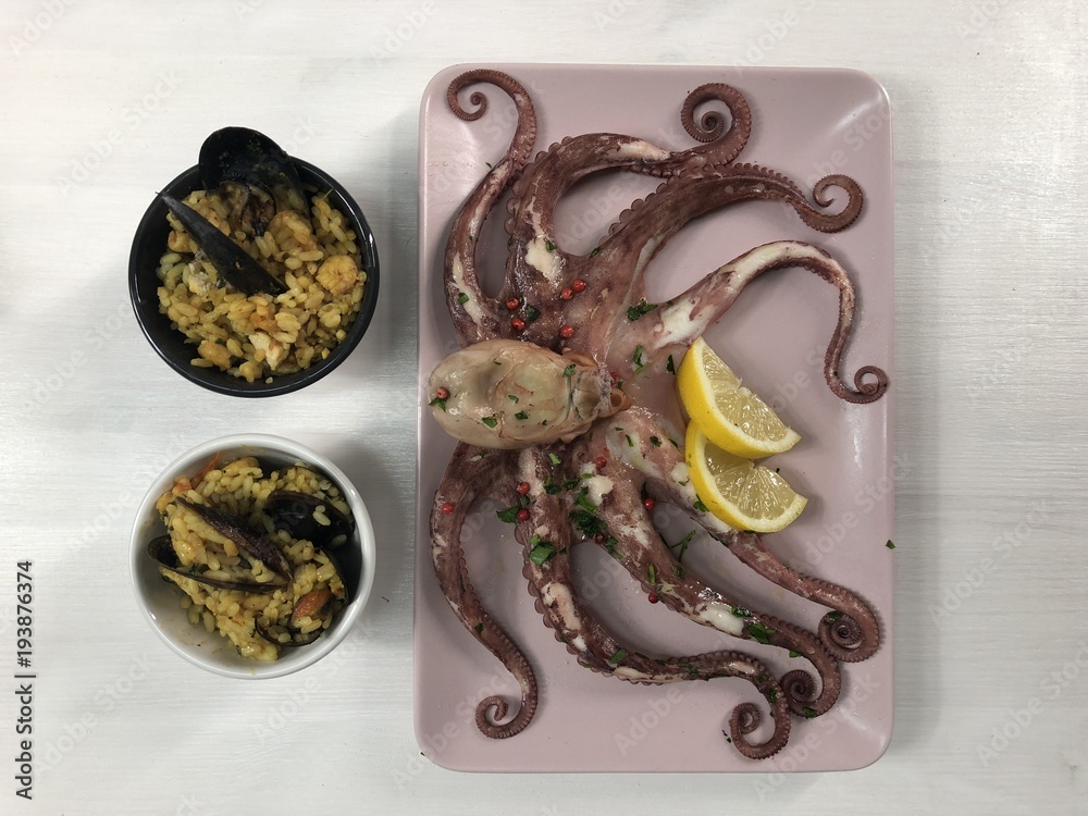 Fried fish,rice with mussels and octopus on dish with lemon and salad.