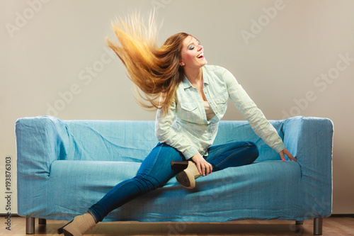 Photos Fashionable girl wearing denim relaxing on couch.