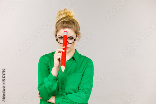 Woman confused thinking, big pencil in hand