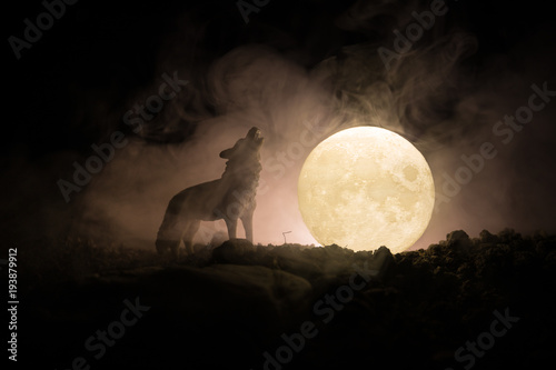Photo Silhouette of howling wolf against dark toned foggy background and full moon or Wolf in silhouette howling to the full moon
