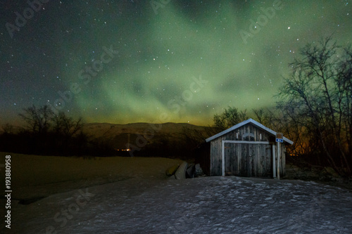 Beautiful aurora borealis over little cottage in Abisko, Lapland, Sweden, northern lights at night photo