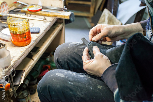 shoemaker repairs shoes in his workshop