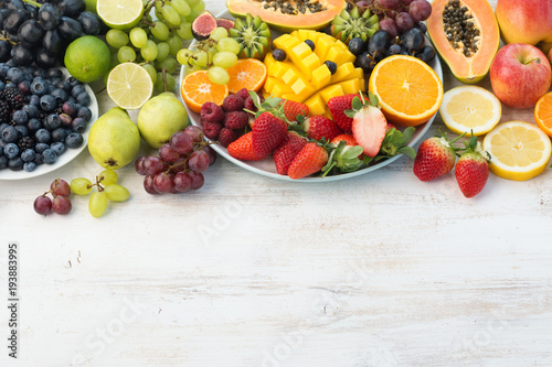 Fresh fruits and vegetables in rainbow colours on the off white table, copy space, selective focus