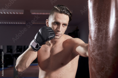 boxer headshot, portrait, face head close up, weaing boxing gloves, punching boxing bag, shirtless, indoors. © HD92