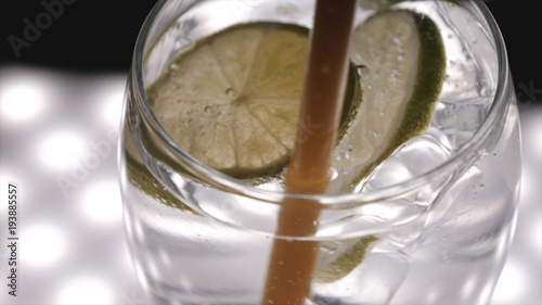 Lemon, lime in a glass with soda water (bubbles), black background.