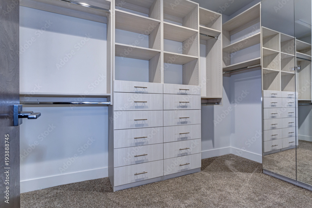 Large walk-in closet with white shelves, drawers