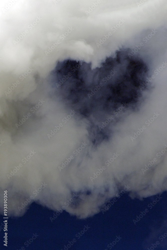 Heart in a white cloud on a dark blue sky. Background for design. Vertical picture.