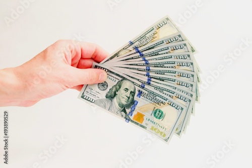 A fan of hundred-dollar bills. A thousand dollars in the left male hand on a white background. How to earn and cash money. Isolated. Close-up.