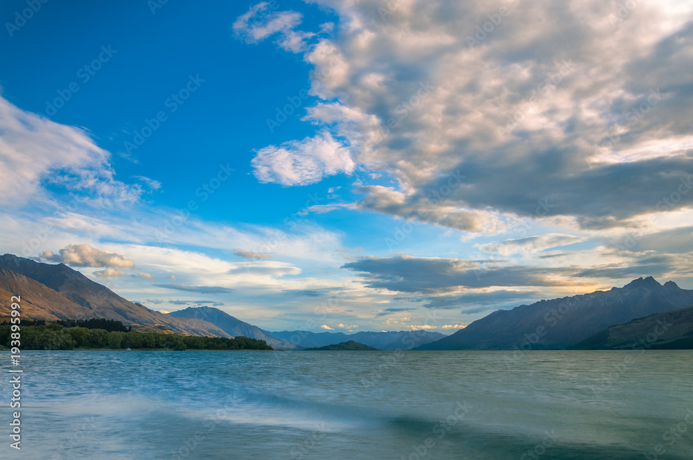 Sunset view from Glenorchy wharf with colorful clouds moving against the beautiful mountain range at the northern end of lake Wakatipu in New Zealand, South Island.