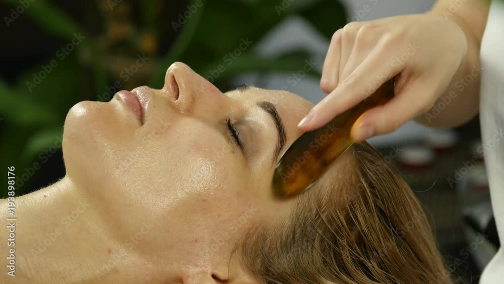 beautician does facial massage for beautiful woman in spa saloon. 4K beautician does facial massage for beautiful woman in spa saloon. 4K