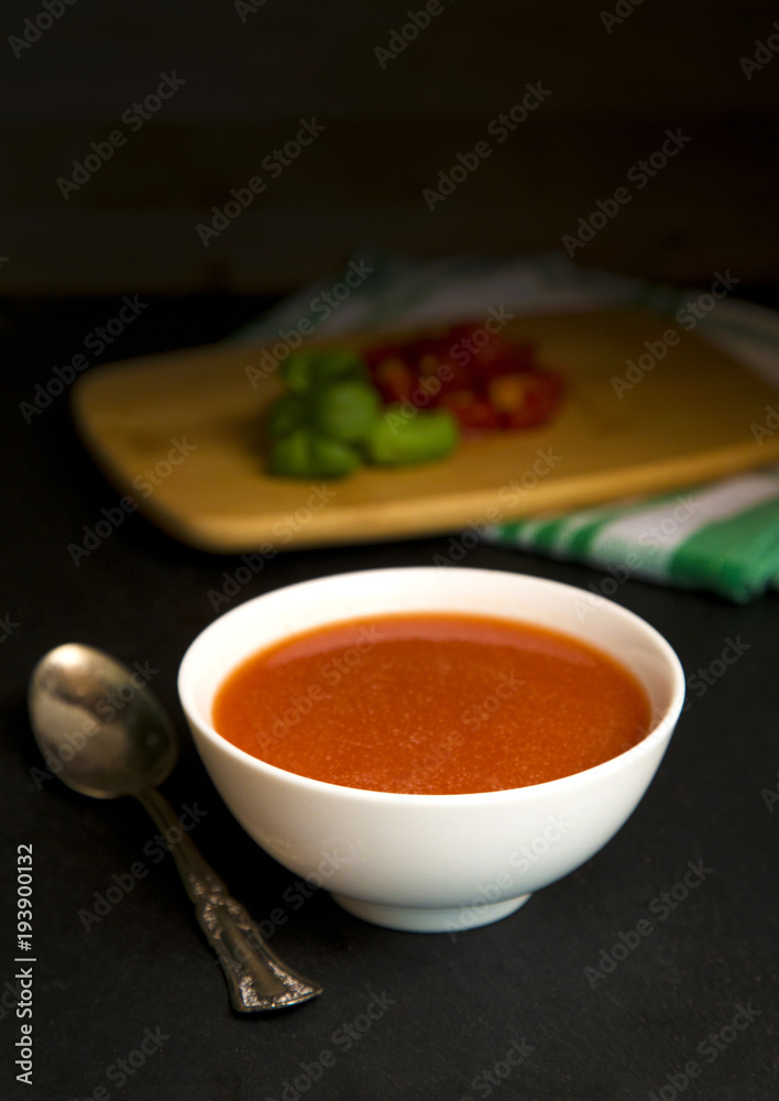 Tomato and Basil Soup in a White Ceramic Bowl in a Dark Environment Tomato and Basil Soup in a White Ceramic Bowl in a Dark Environment