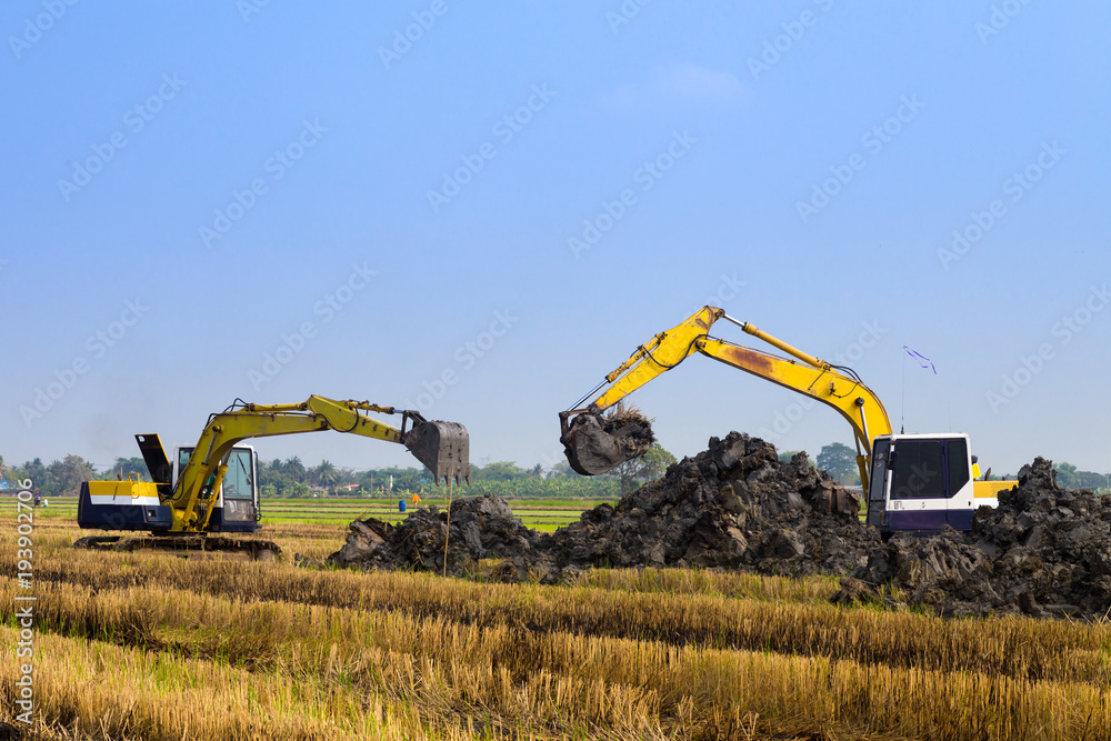 Fototapeta premium excavator backhoes are working in the digging a soil to adjust the postharvest areas in the rice fields. agriculture machinery fo the modern agriculture industry.