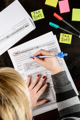 Woman fills the tax form, working with tax documents.  Form 1040 Individual Income Tax return form. United States Tax forms 2016/2017.