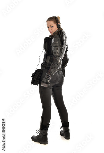 full length portrait of female  soldier wearing black  tactical armour  facing away from camera, isolated on white studio background. © faestock