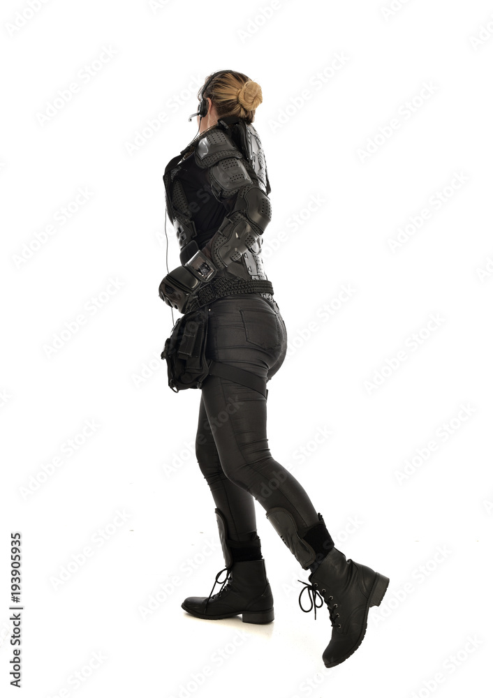 full length portrait of female soldier wearing black tactical armour facing away from camera, isolated on white studio background. full length portrait of female soldier wearing black tactical armour facing away from camera, isolated on white studio background.