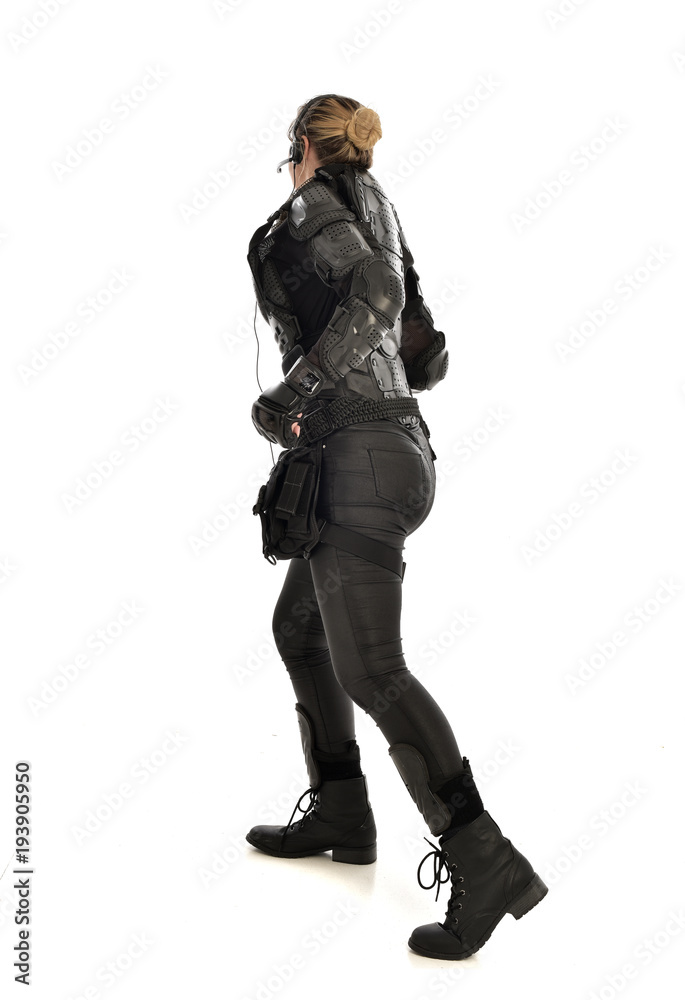 full length portrait of female soldier wearing black tactical armour facing away from camera, isolated on white studio background. full length portrait of female soldier wearing black tactical armour facing away from camera, isolated on white studio background.