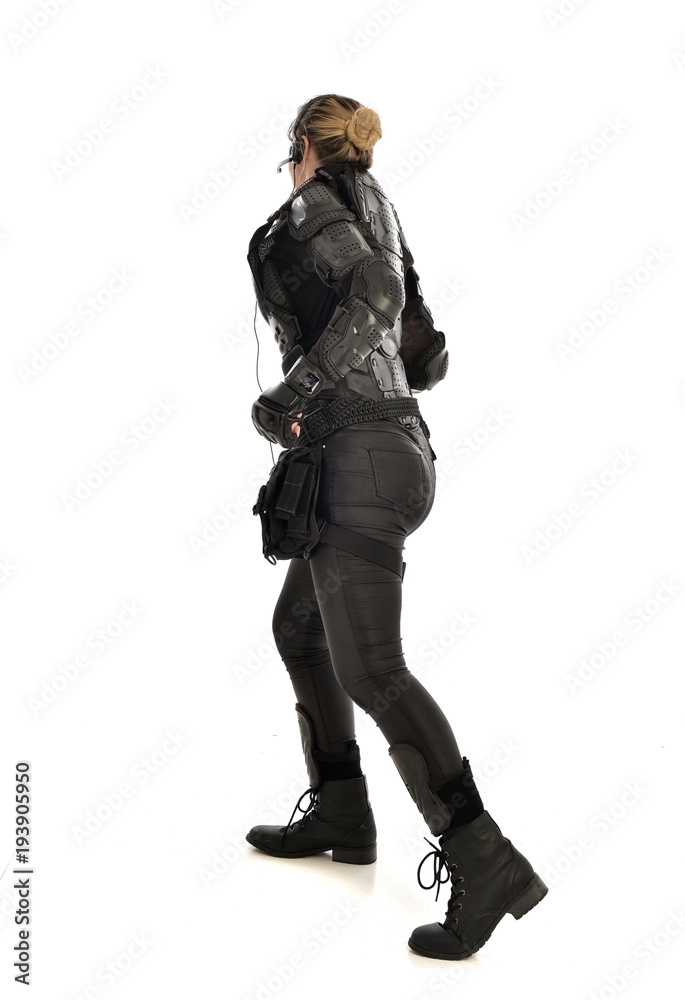 full length portrait of female  soldier wearing black  tactical armour  facing away from camera, isolated on white studio background.