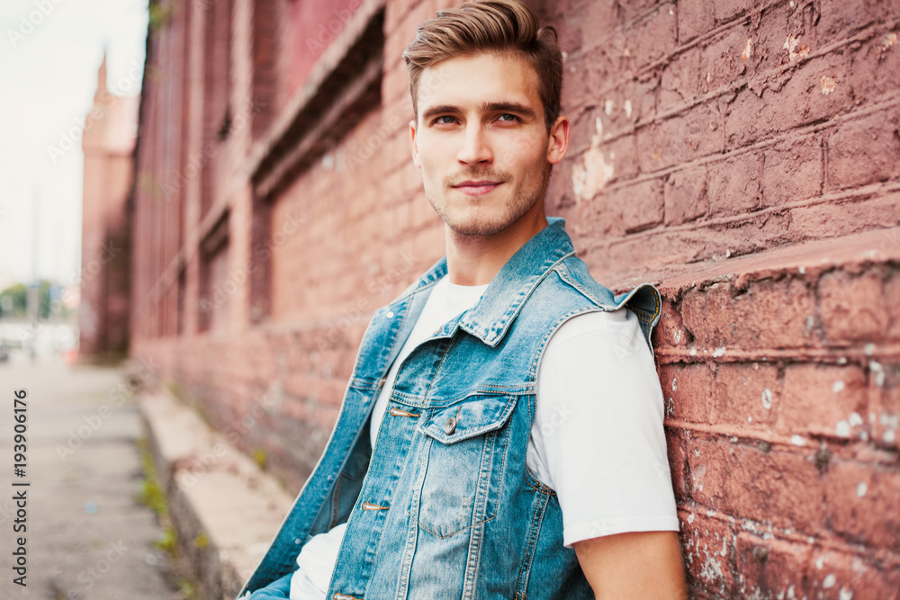 Young man standing against a brick wall