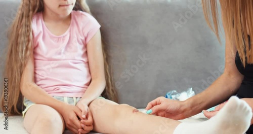 Girl with wound on knee. Mother helping child