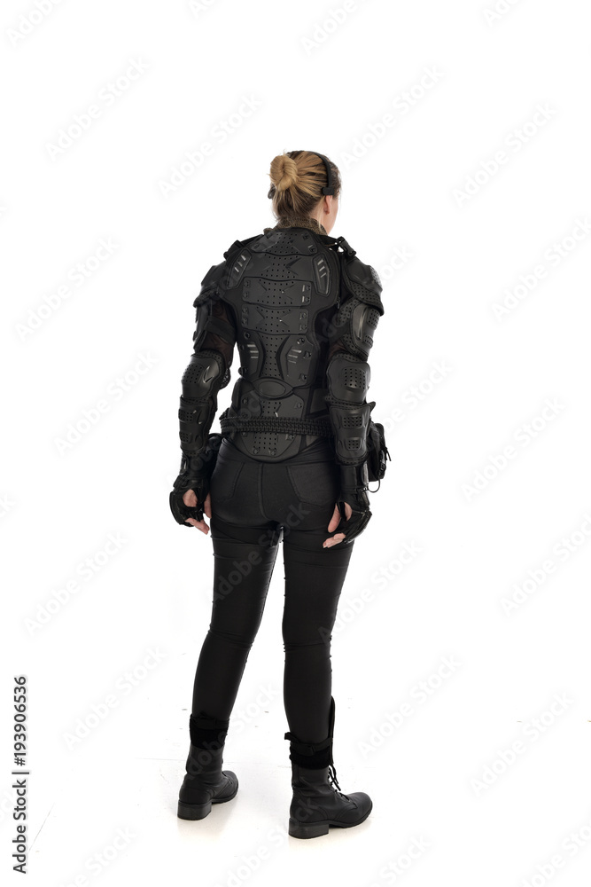 full length portrait of female  soldier wearing black  tactical armour  facing away from camera, isolated on white studio background.