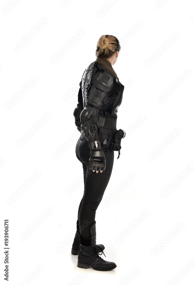 full length portrait of female  soldier wearing black  tactical armour  facing away from camera, isolated on white studio background.