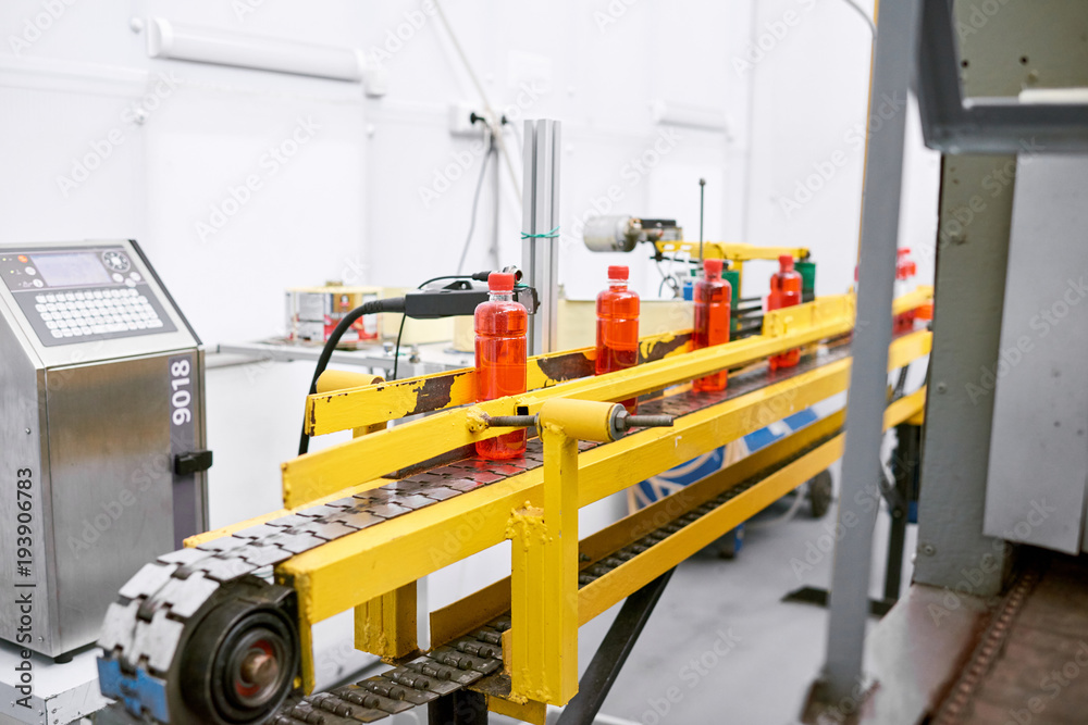 Interior of modern sport nutrition factory: conveyor belt with bottles, white walls, no people Interior of modern sport nutrition factory: conveyor belt with bottles, white walls, no people