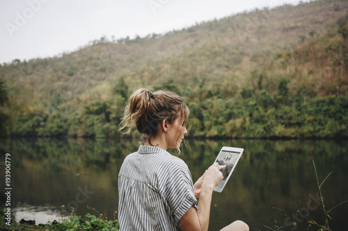 Woman alone in nature using a digital tablet internet connection and travel concept photo