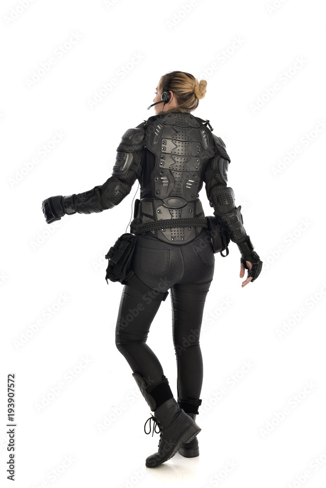 full length portrait of female soldier wearing black tactical armour facing away from camera, isolated on white studio background. full length portrait of female soldier wearing black tactical armour facing away from camera, isolated on white studio background.