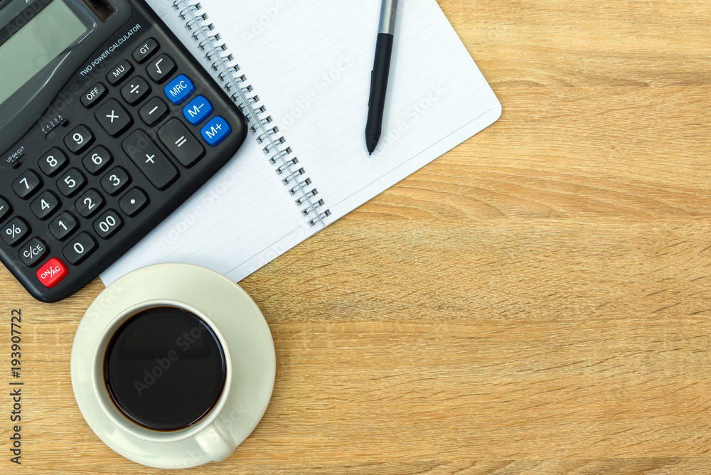 Calculator and cup of coffee with note on working table with copy space top view.