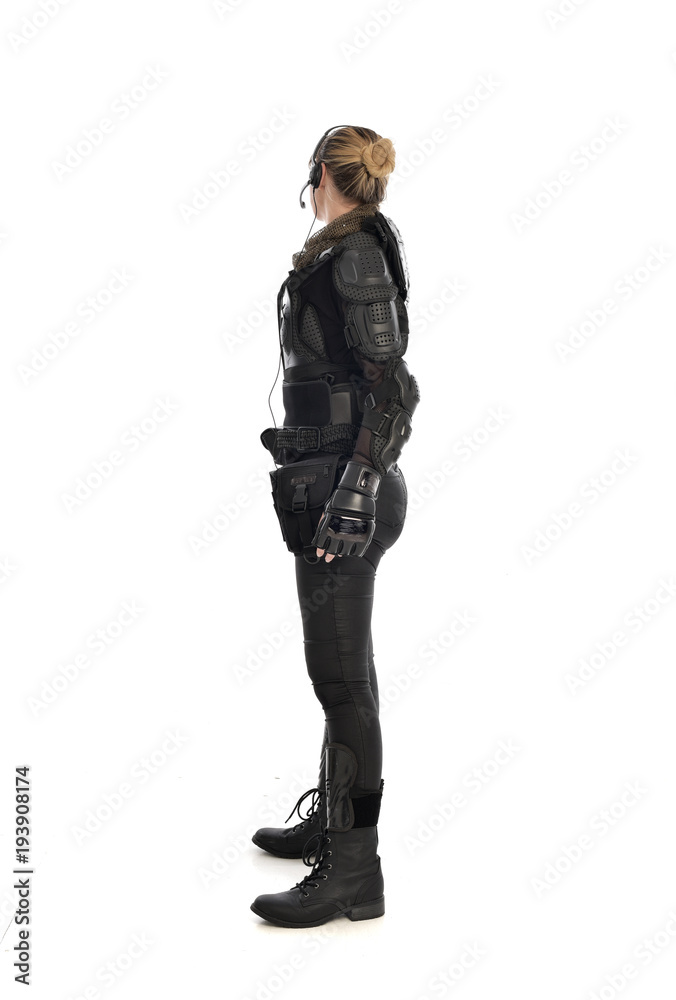full length portrait of female soldier wearing black tactical armour facing away from camera, isolated on white studio background. full length portrait of female soldier wearing black tactical armour facing away from camera, isolated on white studio background.