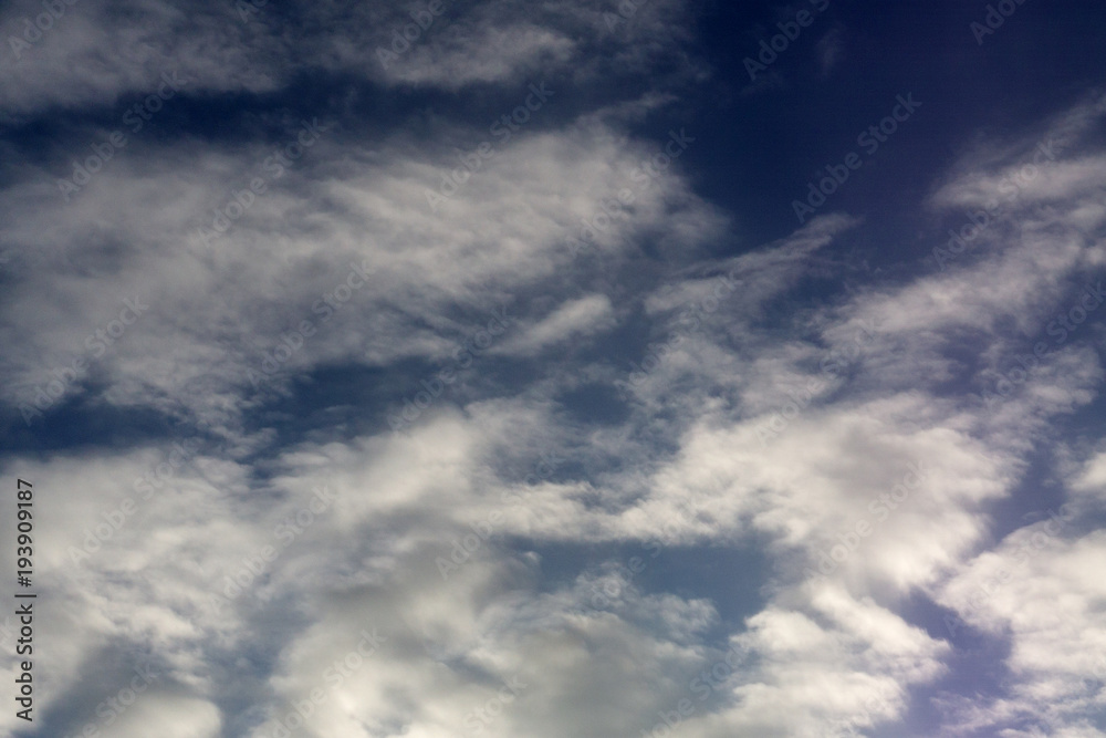 Blue sky with fleecy clouds, may be used as background .