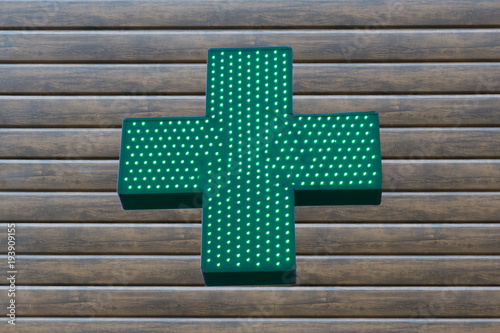Neon green cross sign on wooden background