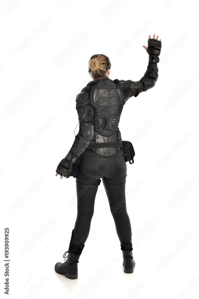 full length portrait of female  soldier wearing black  tactical armour  facing away from camera, isolated on white studio background.