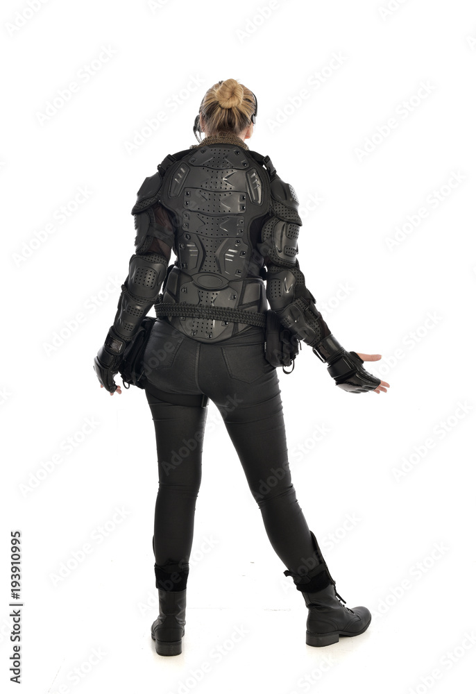 full length portrait of female soldier wearing black tactical armour facing away from camera, isolated on white studio background. full length portrait of female soldier wearing black tactical armour facing away from camera, isolated on white studio background.
