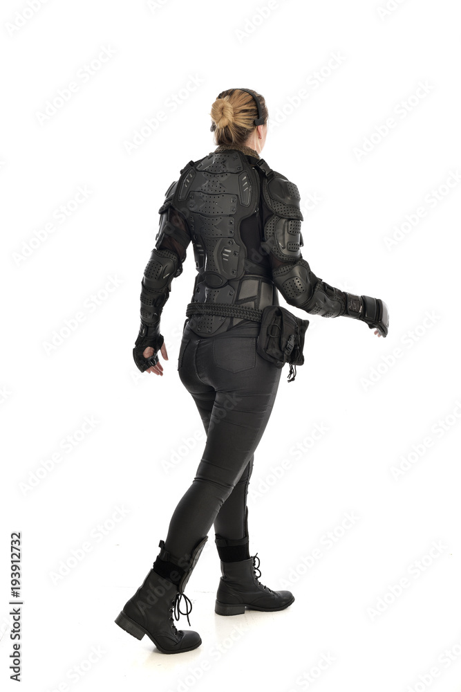 full length portrait of female  soldier wearing black  tactical armour  facing away from camera, isolated on white studio background.