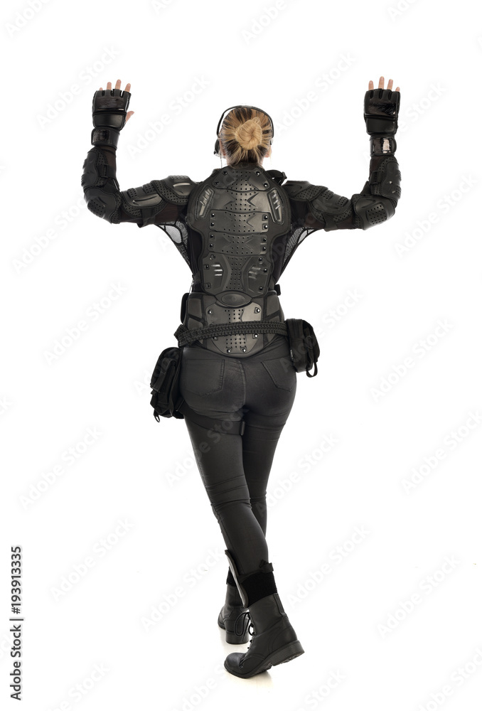 full length portrait of female soldier wearing black tactical armour facing away from camera, isolated on white studio background. full length portrait of female soldier wearing black tactical armour facing away from camera, isolated on white studio background.