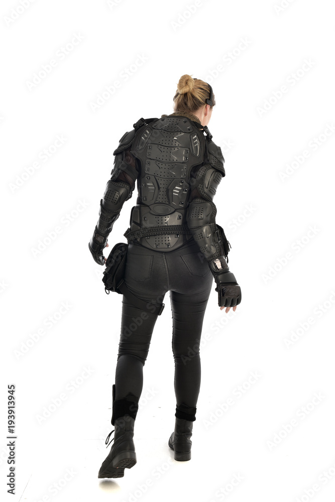 full length portrait of female soldier wearing black tactical armour facing away from camera, isolated on white studio background. full length portrait of female soldier wearing black tactical armour facing away from camera, isolated on white studio background.
