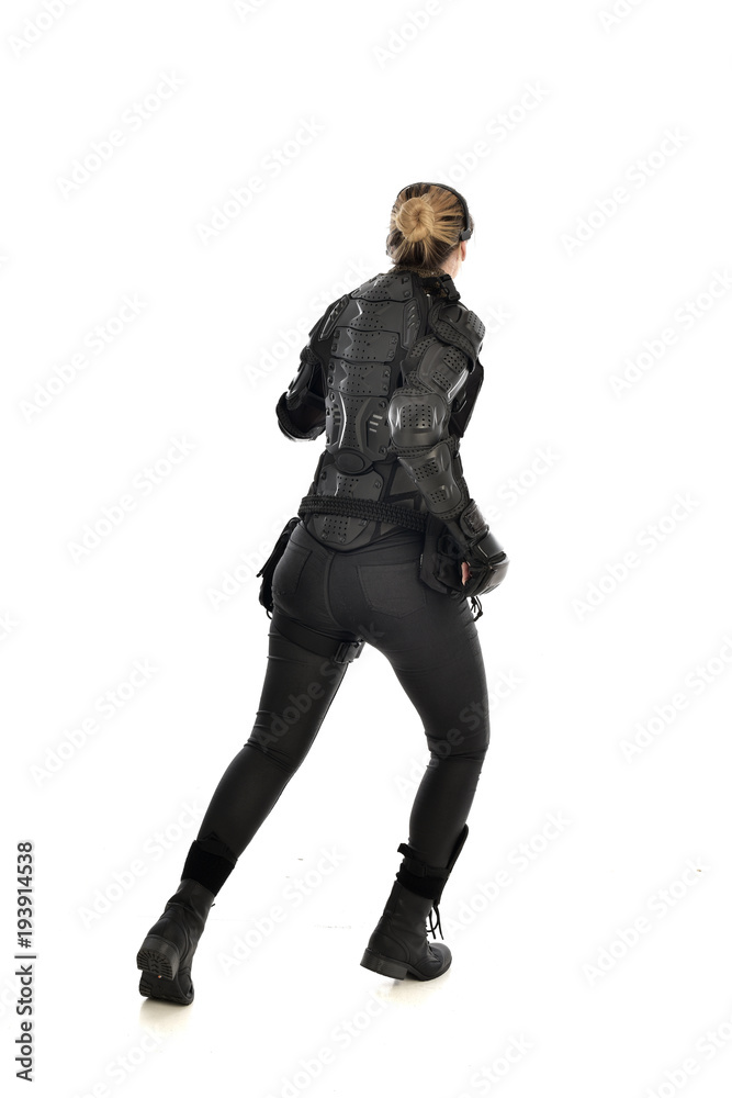 full length portrait of female soldier wearing black tactical armour facing away from camera, isolated on white studio background. full length portrait of female soldier wearing black tactical armour facing away from camera, isolated on white studio background.