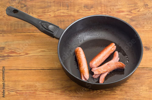 Photography Fried vienna sausages on the frying pan on rustic table