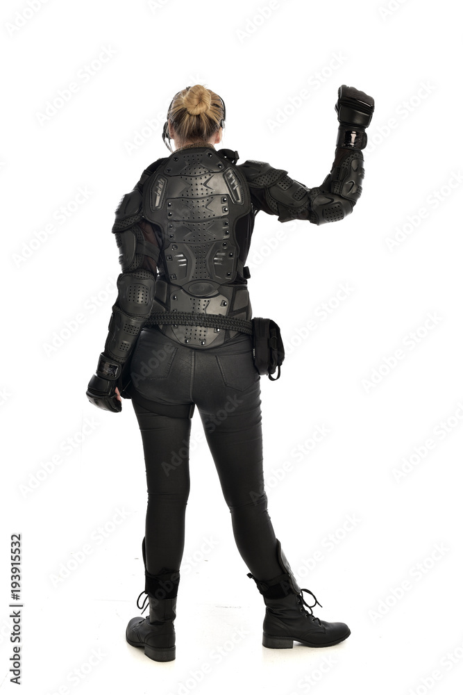 full length portrait of female soldier wearing black tactical armour facing away from camera, isolated on white studio background. full length portrait of female soldier wearing black tactical armour facing away from camera, isolated on white studio background.