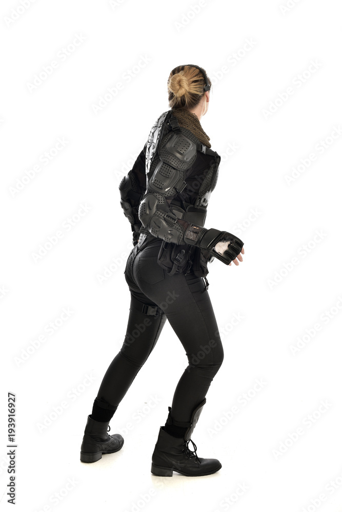 full length portrait of female soldier wearing black tactical armour facing away from camera, isolated on white studio background. full length portrait of female soldier wearing black tactical armour facing away from camera, isolated on white studio background.