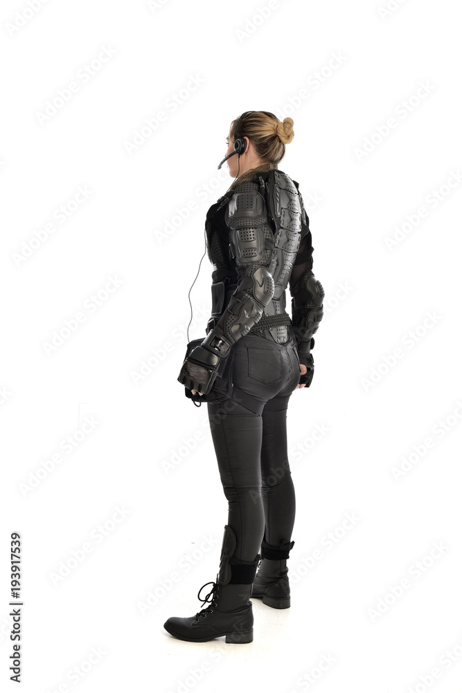 full length portrait of female soldier wearing black tactical armour facing away from camera, isolated on white studio background. full length portrait of female soldier wearing black tactical armour facing away from camera, isolated on white studio background.