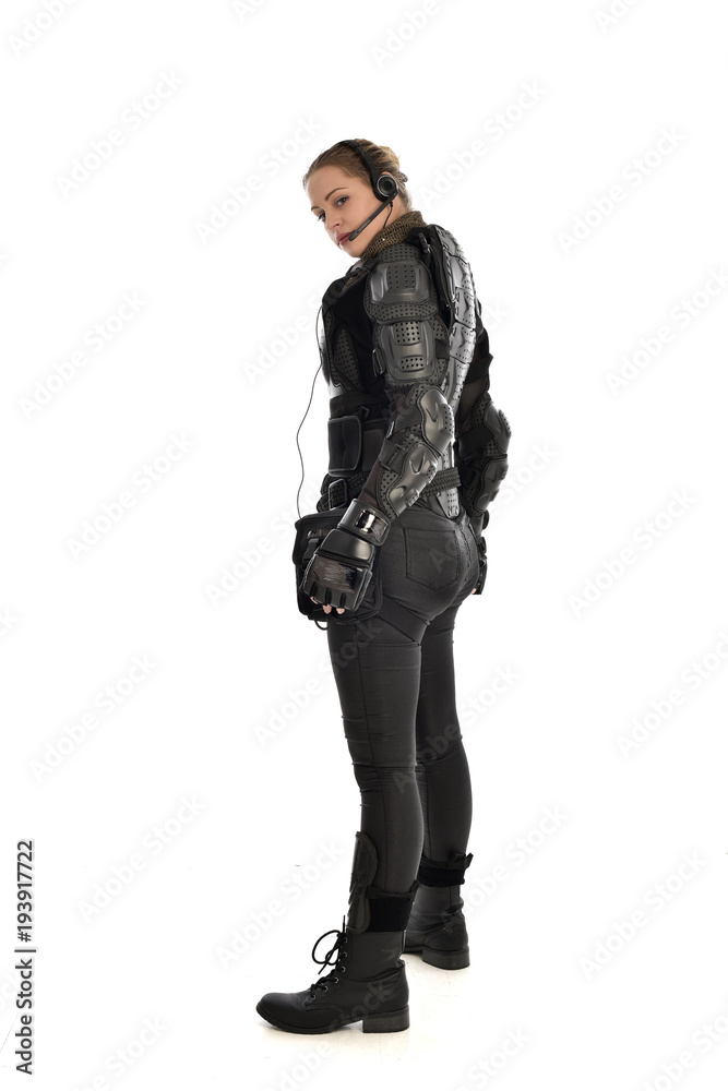 full length portrait of female soldier wearing black tactical armour facing away from camera, isolated on white studio background. full length portrait of female soldier wearing black tactical armour facing away from camera, isolated on white studio background.