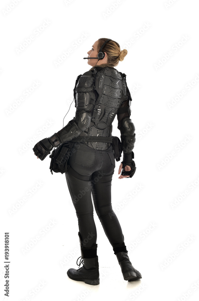 full length portrait of female soldier wearing black tactical armour facing away from camera, isolated on white studio background. full length portrait of female soldier wearing black tactical armour facing away from camera, isolated on white studio background.