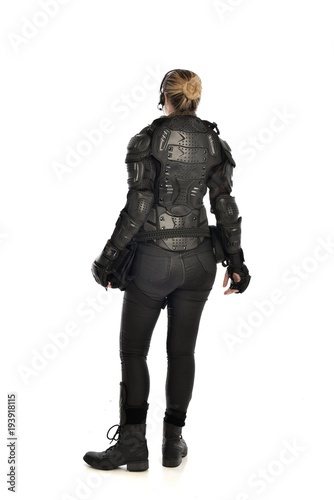 full length portrait of female  soldier wearing black  tactical armour  facing away from camera, isolated on white studio background.