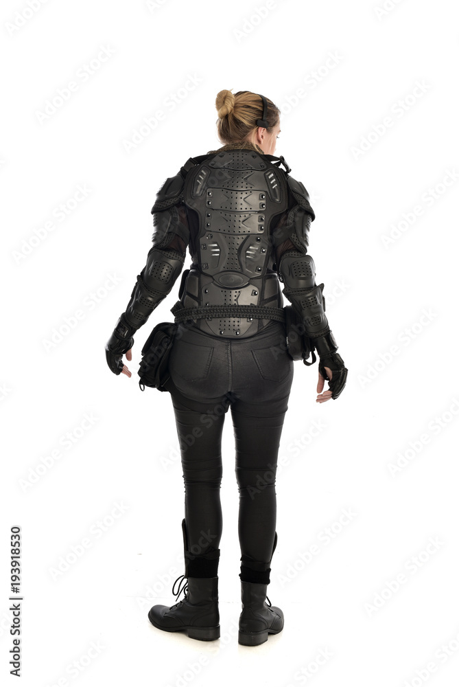 full length portrait of female  soldier wearing black  tactical armour  facing away from camera, isolated on white studio background.