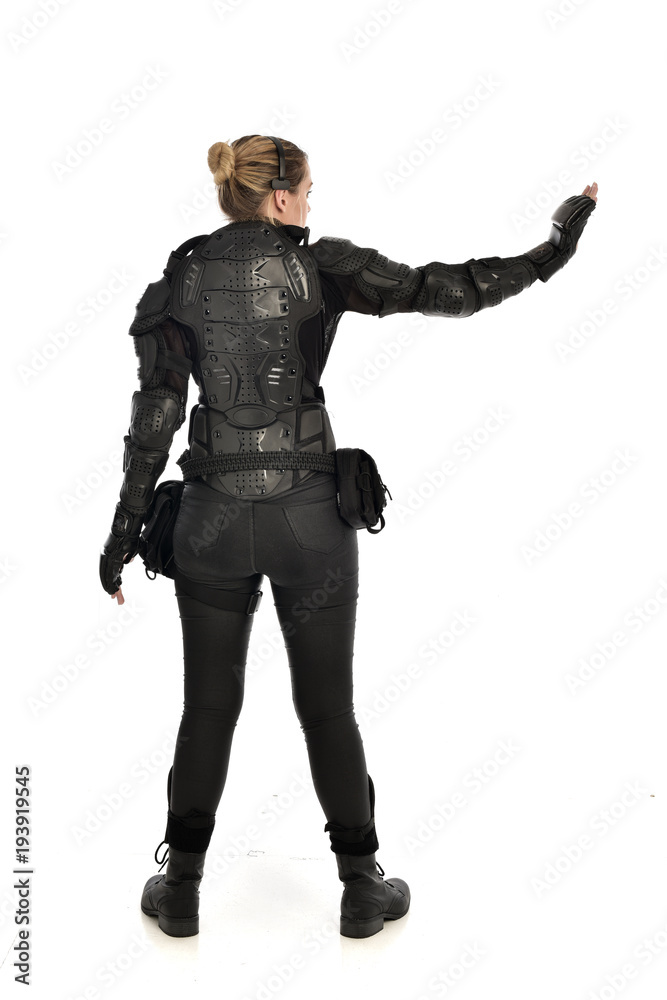 full length portrait of female  soldier wearing black  tactical armour  facing away from camera, isolated on white studio background.