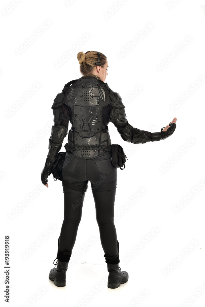 full length portrait of female soldier wearing black tactical armour facing away from camera, isolated on white studio background. full length portrait of female soldier wearing black tactical armour facing away from camera, isolated on white studio background.