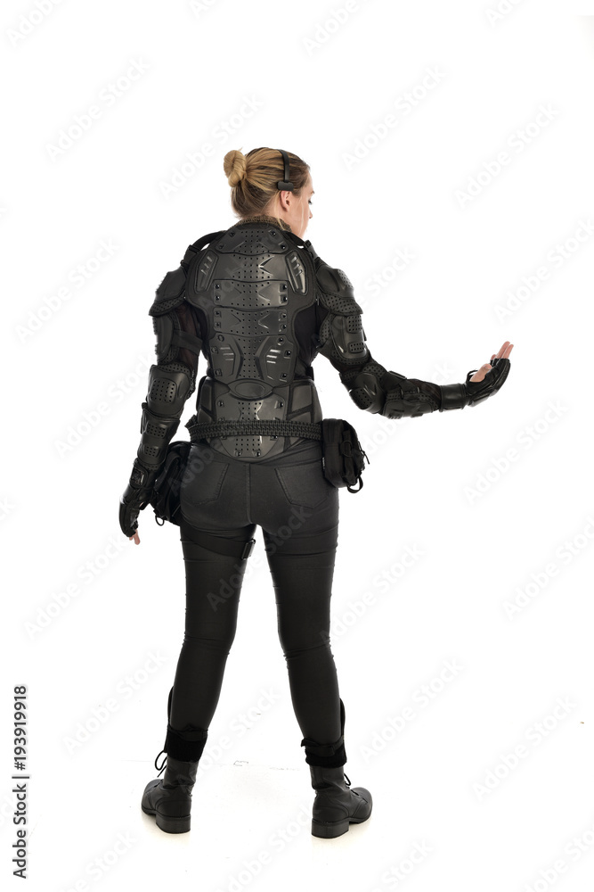 full length portrait of female  soldier wearing black  tactical armour  facing away from camera, isolated on white studio background.